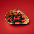 BlackBerry and Raspberry flavoured black and red coloured jelly sweets with sprinkles on in a gold bowl on a red background 