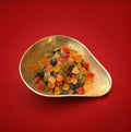 Fruit and liquorice flavoured Lion Midget Gems in a gold bowl with a red background 
