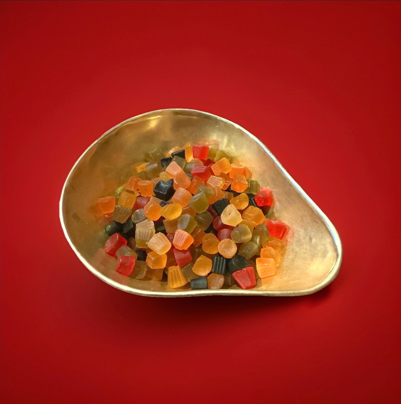 Fruit and liquorice flavoured Lion Midget Gems in a gold bowl with a red background 
