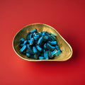 Dark and light blue raspberry flavoured sweets in a gold bowl with a red background 
