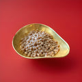 Hard boiled aniseed flavoured pips in a gold bowl on a red background 