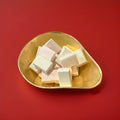 White and pink coloured strawberry flavoured sherbet blocks in a gold bowl on a red background 