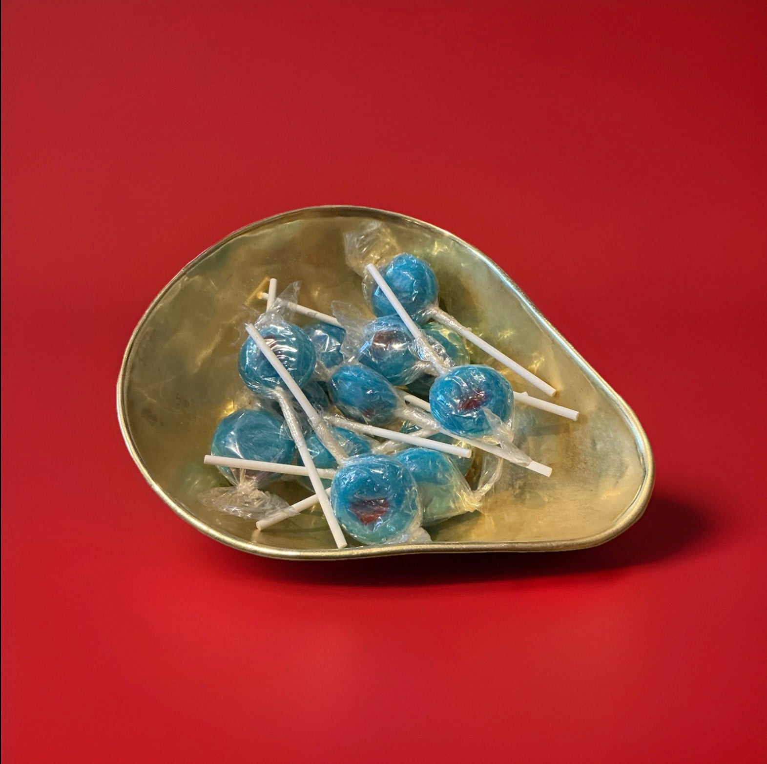 Individually wrapped hard boiled blue and red bubblegum flavoured lolly in a gold bowl on a red background 