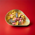 Animal shaped pink yellow and brown chocolate in a gold bowl on a red background 