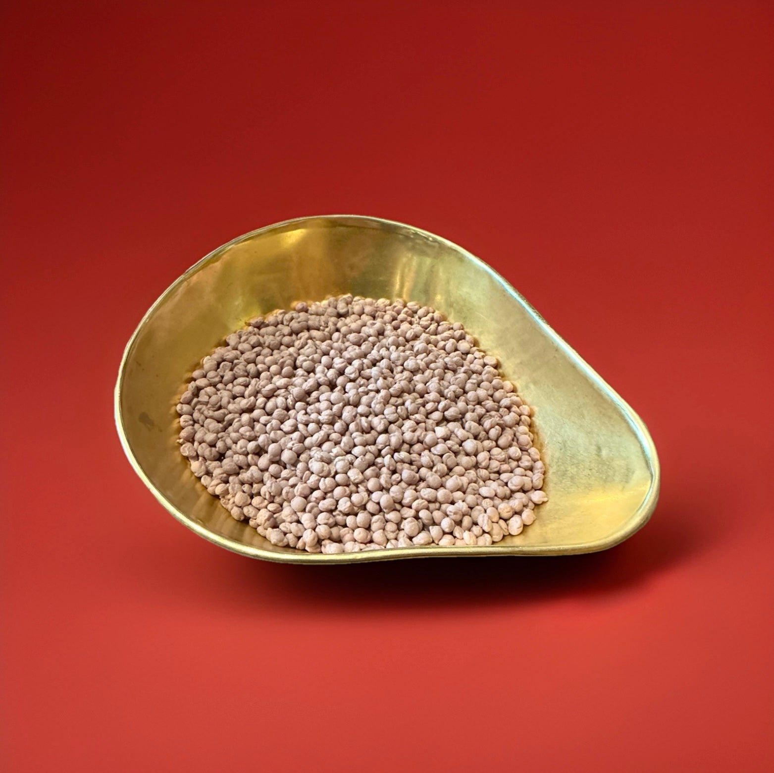 Brown coloured cola flavoured millions in a gold bowl on a red background 