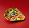 Multicoloured jelly American hard gum sweets with a sugar coating in a gold bowl on a red background 