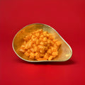 Hard boiled iron brew flavoured cushion shaped sweets in a gold bowl with a red background 