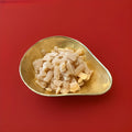 Hard boiled herbal flavoured tablets with a sugar coating in a gold bowl on a red background 