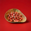 White red and brown striped round hard boiled sweets with a cola flavour and a fizzy sherbet centre in a gold bowl with a red background 