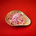 Pink strawberry flavoured fondant tubes in a gold bowl on a red background 