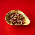 Brown and white cola bottle shaped and flavoured jelly sweets in a gold bowl on a red background 