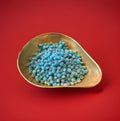 Hard boiled blue raspberry flavoured pips in a gold bowl on a red background 