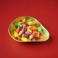 Multicoloured mixed fruit flavoured hard boiled sweets with a sherbet centre in a gold bowl with a red background 