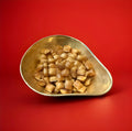 Toffee flavoured hard boiled cushion shaped sweets in a gold bowl with a red background 