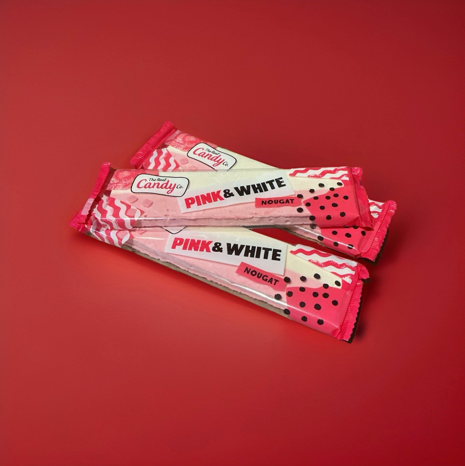 Pink and white coloured nougat bar in a pink and white wrapper on a red background 