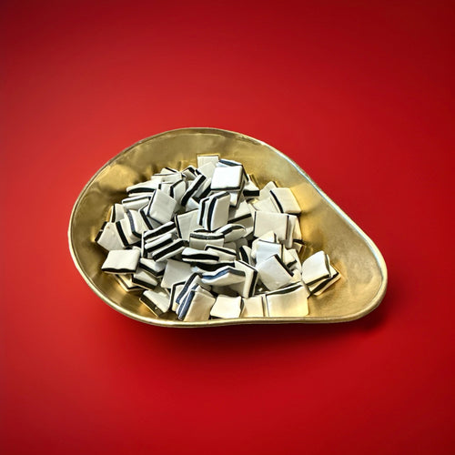 1 kilogram of liquorice and mint fondant black and white mints in a gold bowl with a red background 