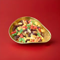 Haribo mini jelly babies in a gold bowl on a red background 