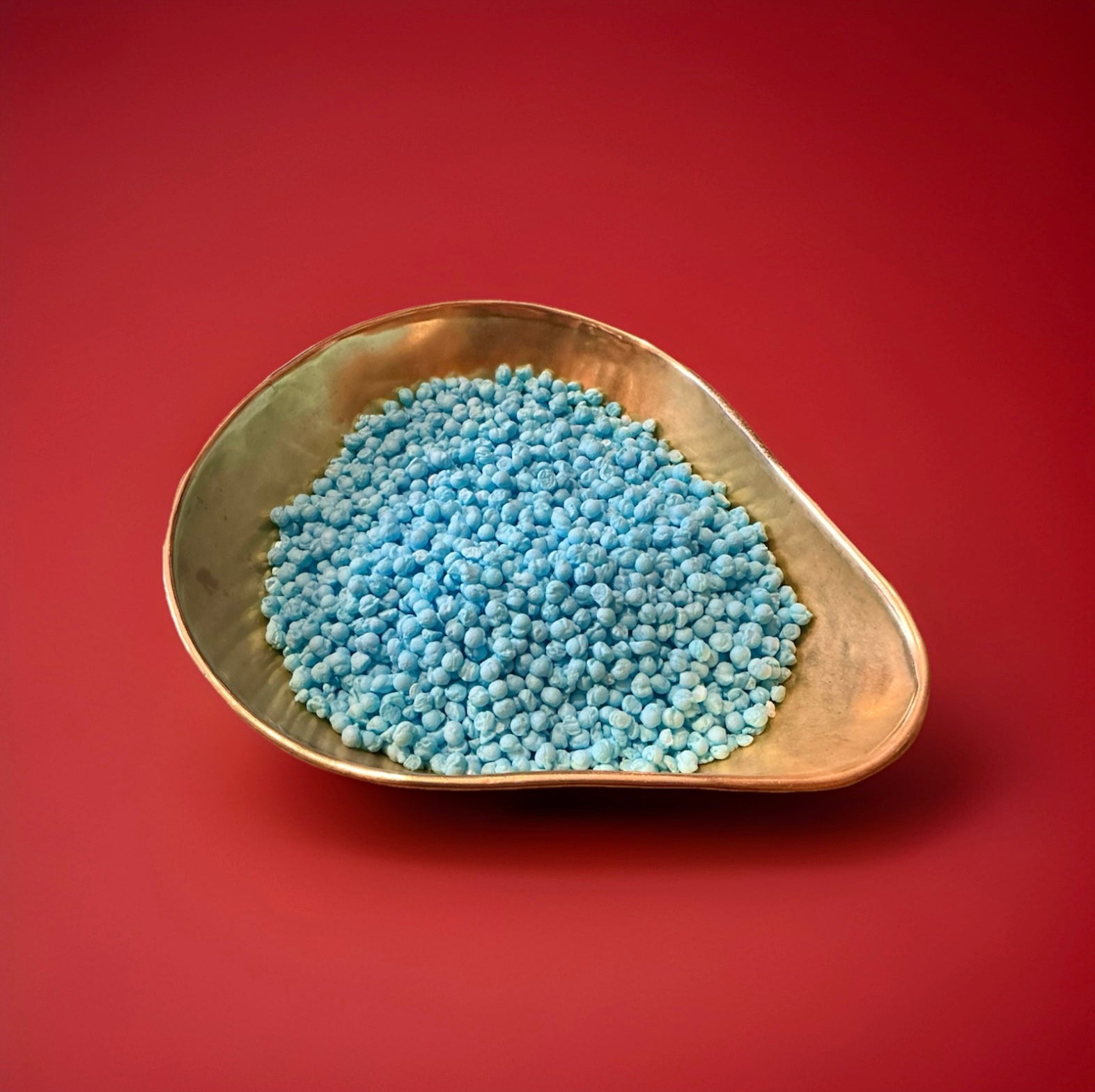 Blue coloured bubblegum flavoured millions in a gold bowl on a red background 