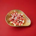 Individually wrapped hard boiled menthol and eucalyptus number 10 drop sweets in a red and white wrapper in a gold bowl on a red background 