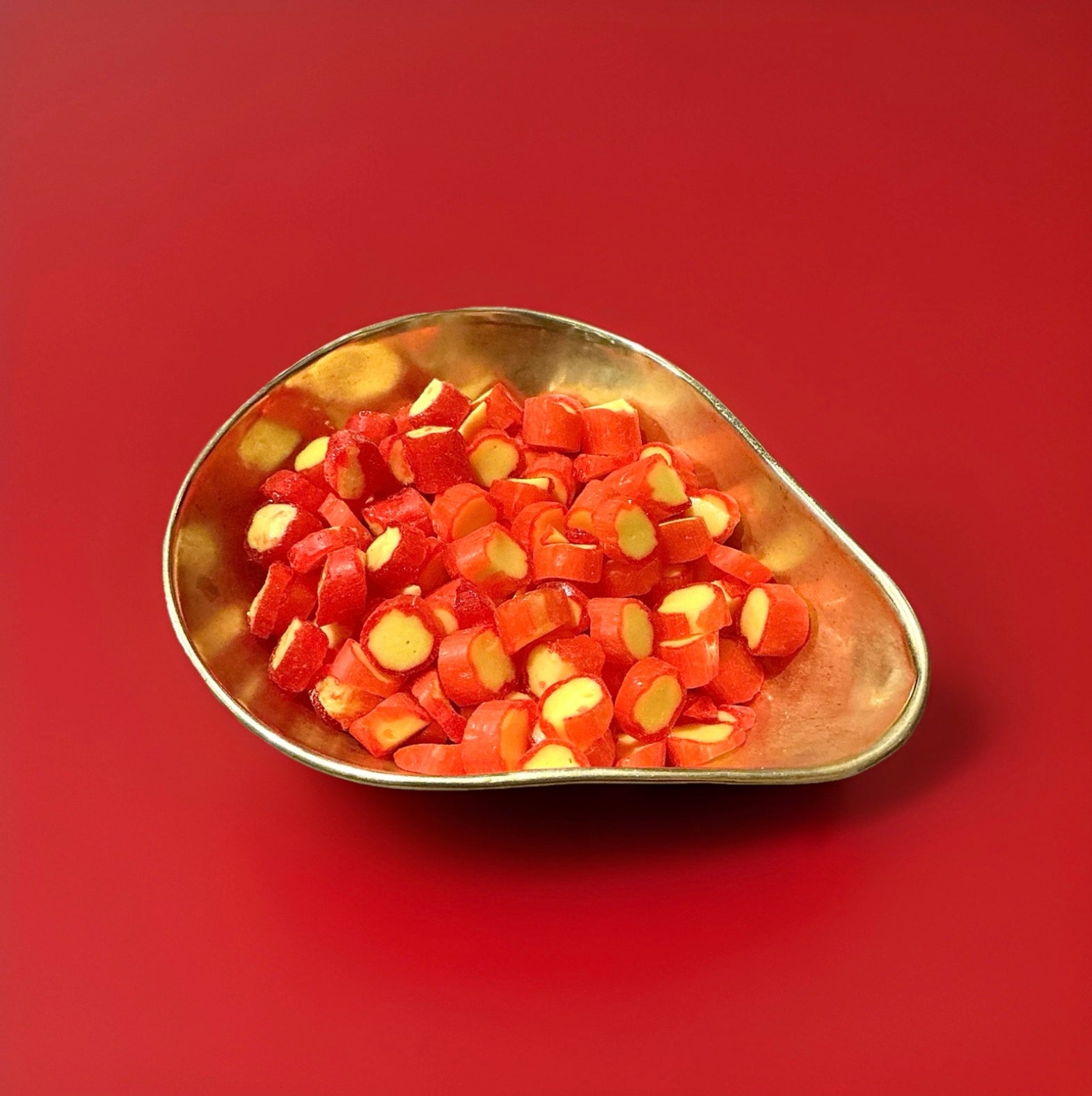 Red and yellow pineapple flavoured rock cuttings in a gold bowl on a red background 