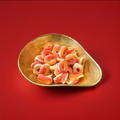 Jelly fizzy peach rings in a gold bowl with a red background 